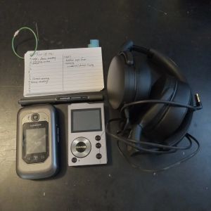 Photograph of a hipster PDA, dumb phone, mp3 player, and headphone.